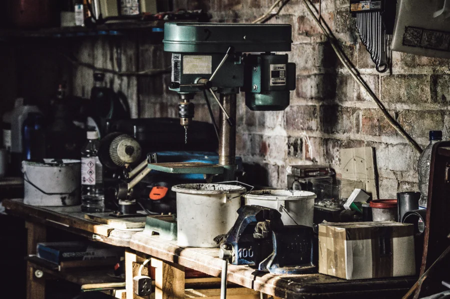 A workshop bench with a drill press and tools